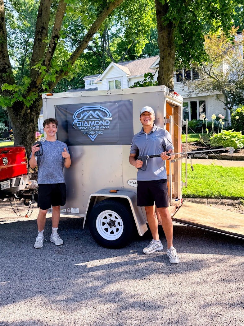 Diamond Spray's team standing with their branded equipment trailer